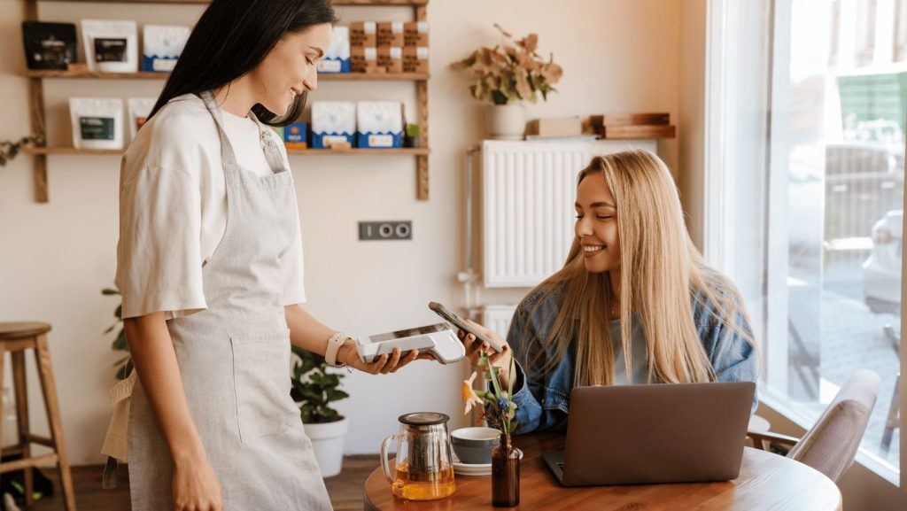 woman paying at a coffee shop using her phone