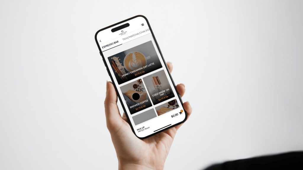 Hand holding a phone with Hometown Coffee & Juice's app open, showing the menu screen 